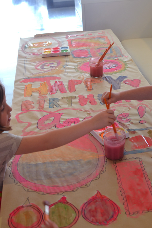 Kids collaborate to make a giant painted birthday banner