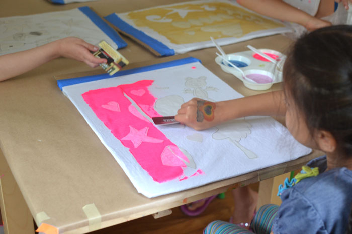 kids design and paint their own backpacks using freezer paper and a scrape painting technique