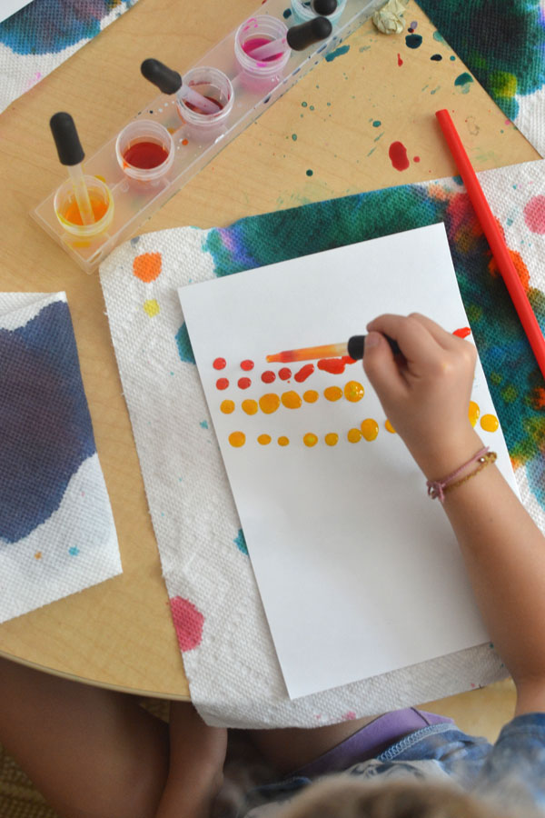 Kids use liquid watercolors and straws to move the paint around on the paper and make colorful art.