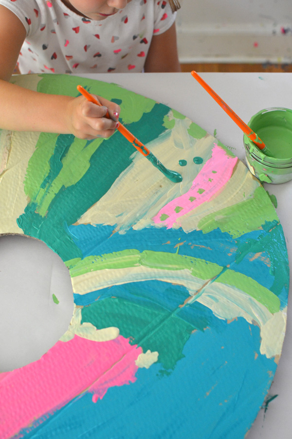 Kids paint and collage giant donuts cut from recycled cardboard.