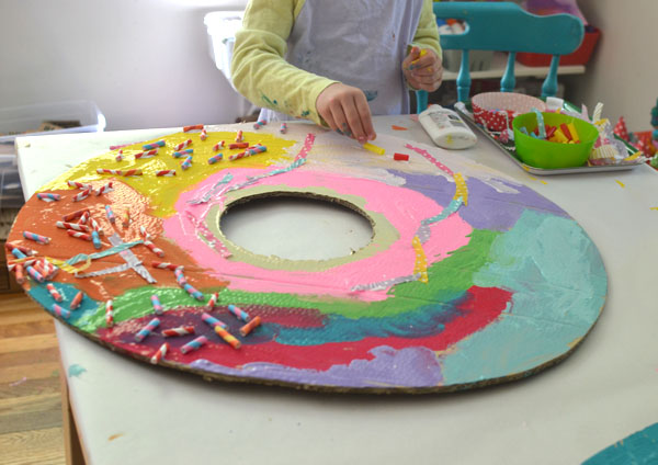 Kids paint and collage giant donuts cut from recycled cardboard.