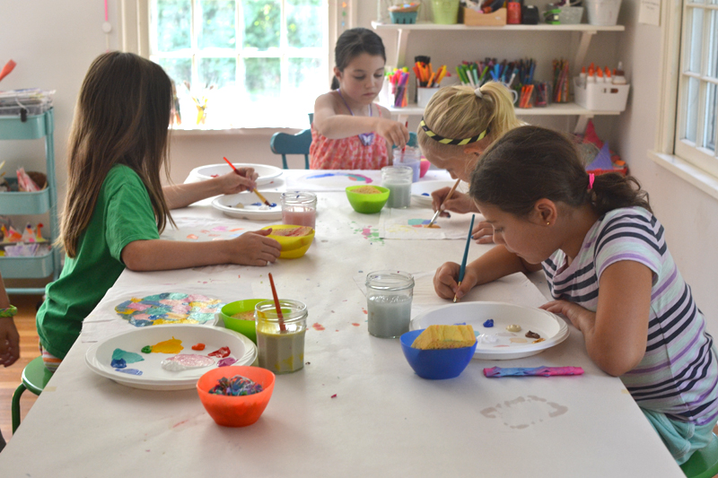 Children learn about acrylic paints by just digging in and experimenting on fabric. Their paintings are then framed in an embroidery hoop. Inspired by artist Kindah Khalidy.
