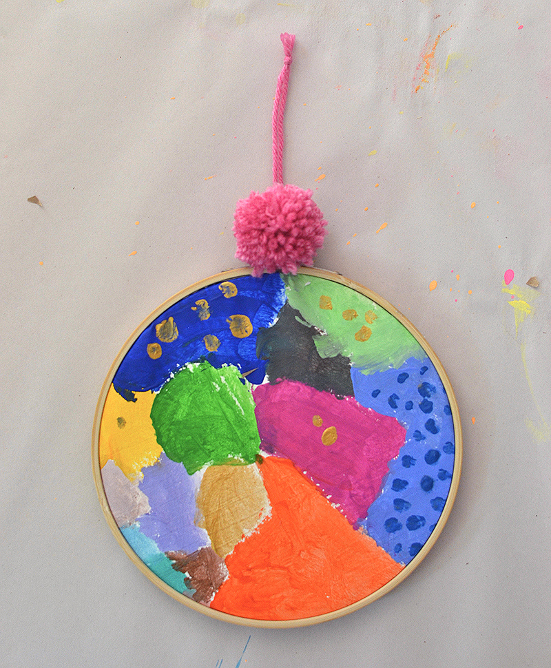 Children learn about acrylic paints by just digging in and experimenting on fabric. Their paintings are then framed in an embroidery hoop. Inspired by artist Kindah Khalidy.