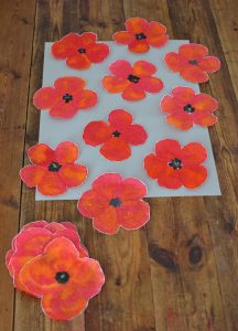 Children paint poppies using coffee filters and liquid watercolors.