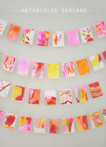 Kids make a garland from small watercolor paintings made with Q-tips and liquid watercolor.