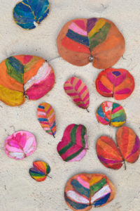 Children and teens paint leaves with water soluble crayons.