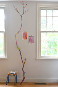 Children collaborate to paint a fallen branch