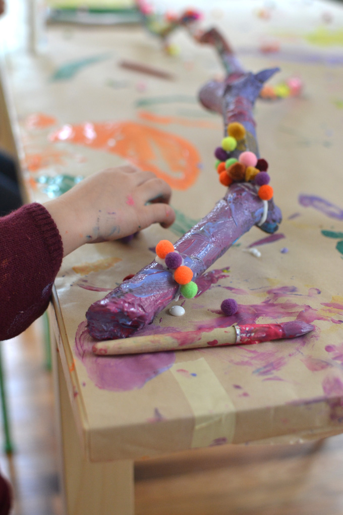 Children collaborate to paint and decorate a large branch. A wonderful process art experience.