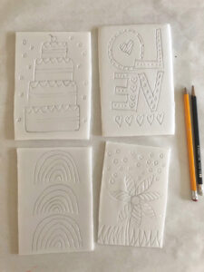 styrofoam sheets on a table with dull pencils, used to make indents into the styrofoam and then roll with paint and make prints
