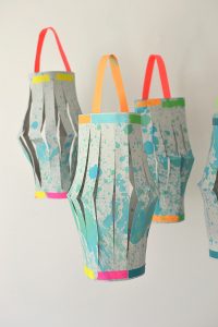 Kids use a splatter paint technique to make the beautiful paper for these lanterns, then they fold, cut, and tape the lanterns all by themselves!
