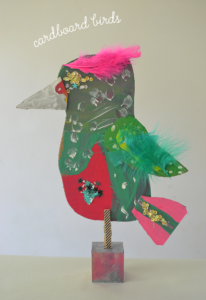 kids make bird sculptures from cardboard, paint, feathers, and a wooden block