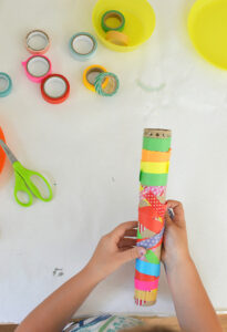 Child wrapping waashi tape around a cardboard tube