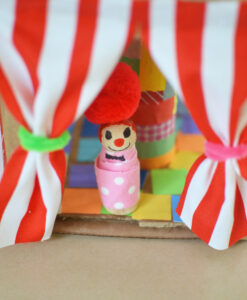 Little decorated peg doll peeking out of circus tent curtains