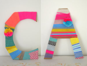 Children wrap cardboard letters with yarn.
