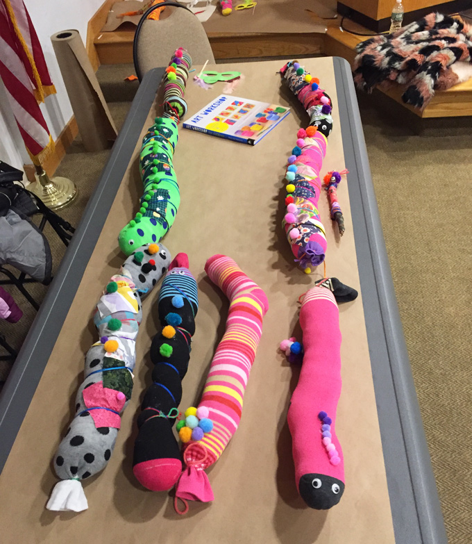 Kids and families make sock caterpillars at a community library event.