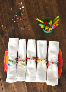 Kids make beaded napkin rings for Thanksgiving with names for each place setting.