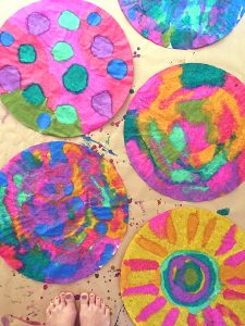 Children paint giant coffee filters hanging on a line. A wonderful process art experience.