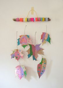 Make a nature mobile with painted leaves and yarn-wrapped twigs.