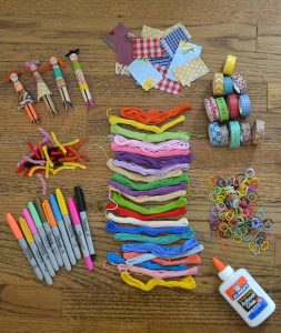 Supplies needed to make wooden peg dolls with fabric scraps and yarn.