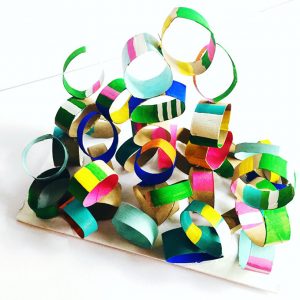 Children use cut up pieces of toilet paper tubes to build sculptures with glue.