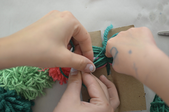 Kids make mobiles from painted pinecones and homemade pom-poms.