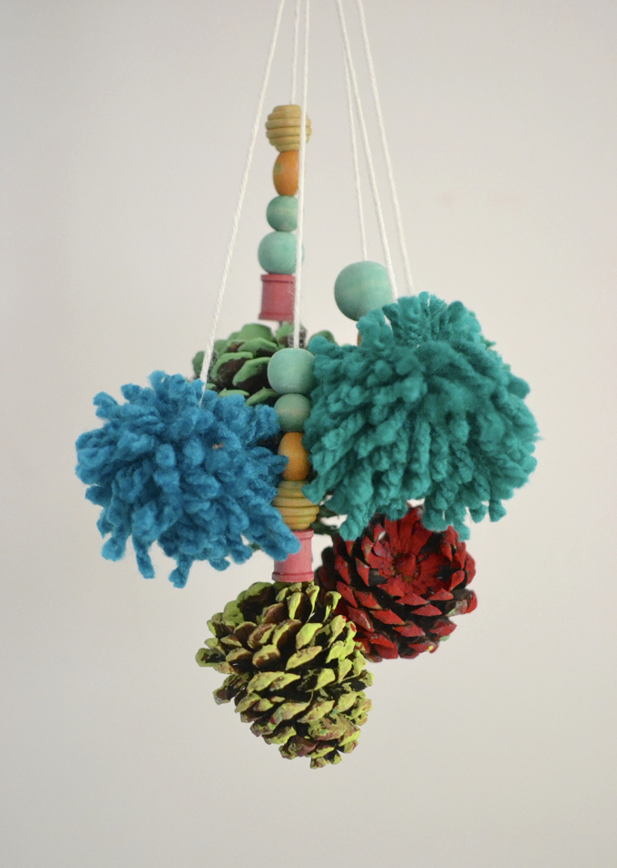 Kids make mobiles from painted pinecones and homemade pom-poms.