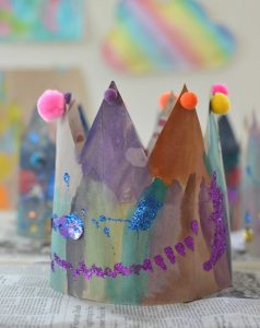 Kids paint and decorate crowns made from paper bags.