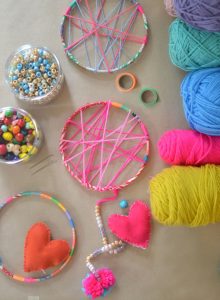 Kids make cream catchers using yarn and sewing hearts.