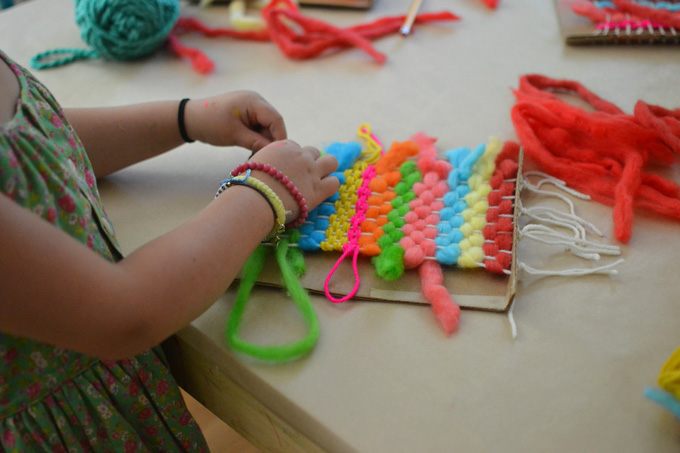 Kids dye their own chunky wool yarn with Koolaid, then make small weaving on cardboard looms.