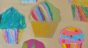 Kids create colorful cardboard cupcakes with oil pastels after studying artist Wayne Thiebaud.