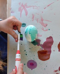 Kids paint eggs with toothbrushes.