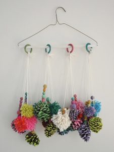 Painting pinecones and homemade pom-poms come together to make these charming mobiles.
