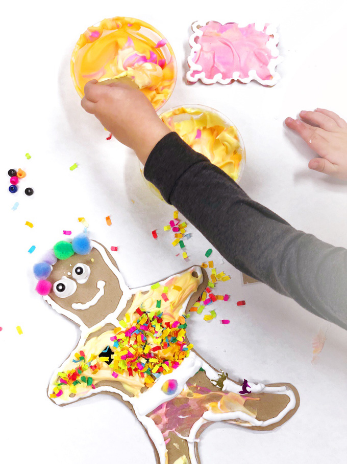 Kids use homemade puffy paint to decorate giant cardboard gingerbread men and cardboard gingerbread houses.