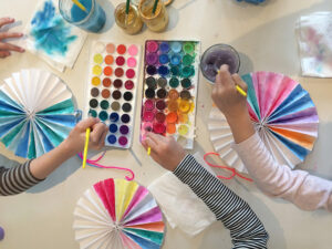Kids paint homemade paper pinwheels at a birthday party.