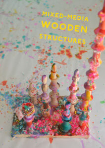 Children make mixed-media wooden structures using wood pieces, liquid watercolor, are yarn.