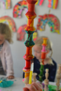 Children make mixed-media wooden sculptures using wood pieces, liquid watercolor, are yarn.