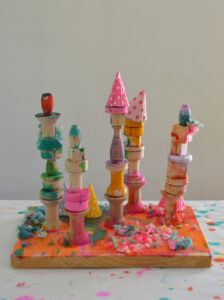 Children make mixed-media wooden sculptures using wood pieces, liquid watercolor, are yarn.