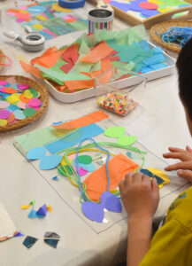 Children stick collage material to contact paper to make colorful and playful wall art.