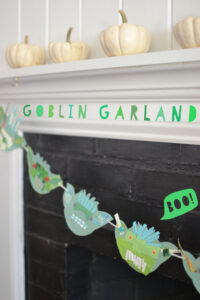 Kids make goblin garland with cardboard and collage material for a Halloween decoration.