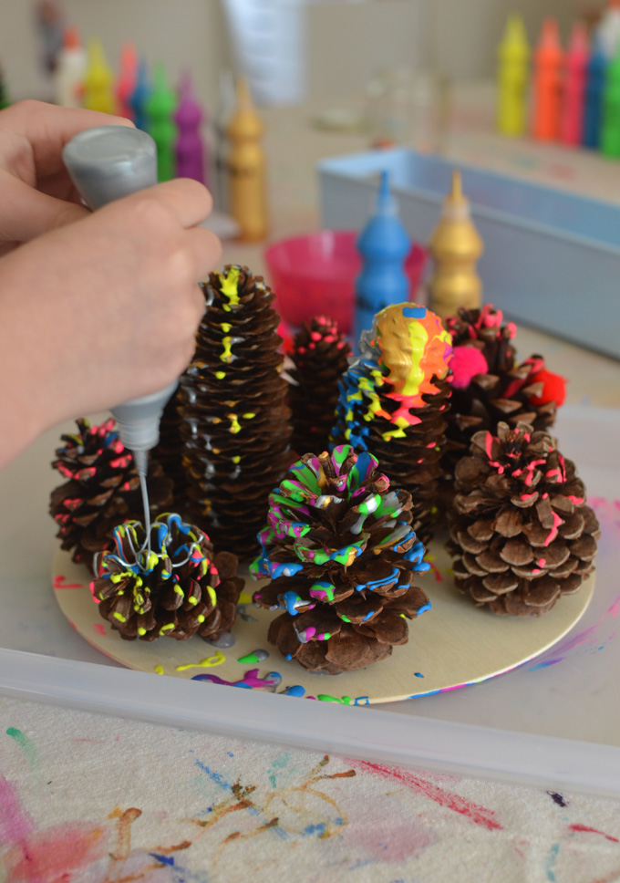 Kids use a drip paint technique to embellish pinecones and create a drippy forest.