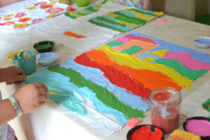 Kids paint with glue on fabric to make batik art, inspired by artist Anna Blatman.