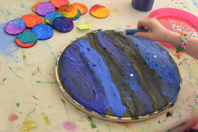 Make a solar system with cotton rounds, watercolor, acrylics, fabric and an embroidery hoop. A wonderful, open-ended art activity to celebrate Earth day!