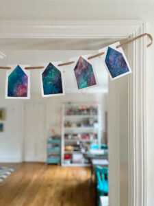 Make painted house garland using a liquid watercolor and tape resist technique.
