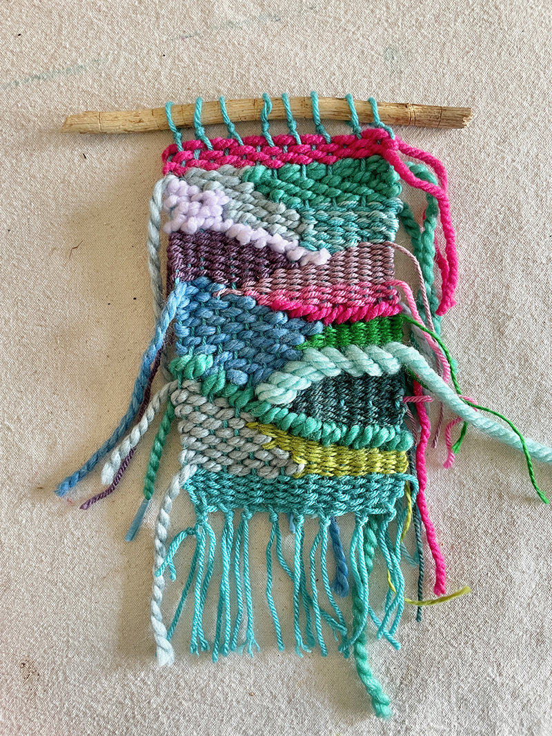 A finished doodle weaving on a stick, the ends still need to be tucked in