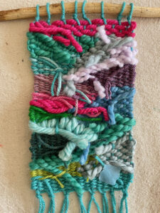 The back of a colorful doodle weaving with the ends tucked into the warp and weft