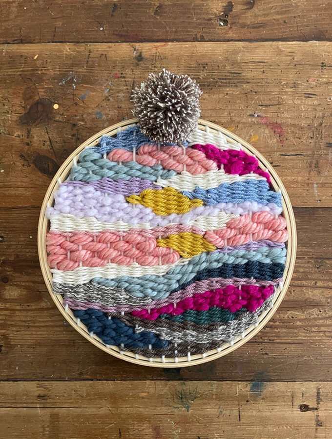 doodle weaving made with colorful yarn in a round embroidery hoop