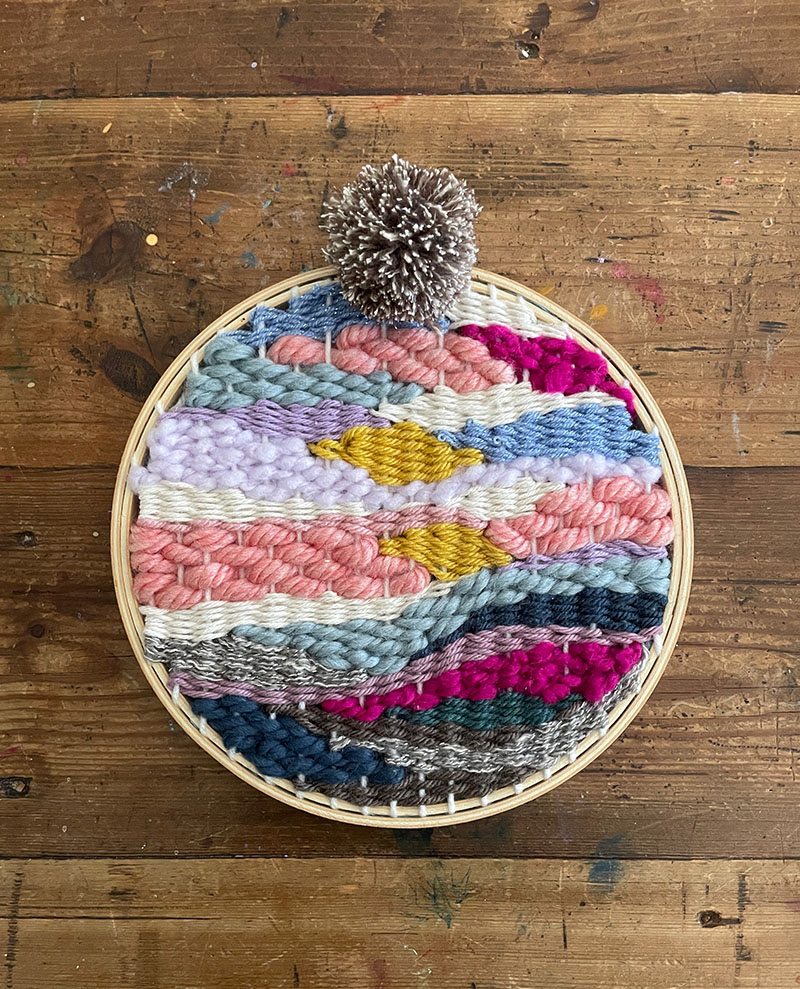 doodle weaving made with colorful yarn in a round embroidery hoop