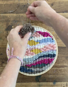 Adding a homemade pom-pom to the round doodle weaving