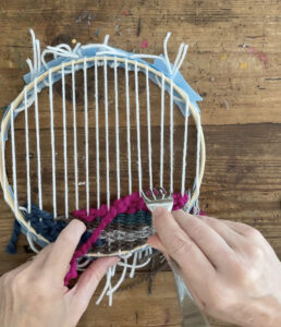 doodle weaving with yarn using a fork as a tool to press down the weft