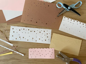 Construction paper with decorative cut edge and holes punches to make paper luminaries